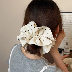 Oversized white chiffon scrunchie with black heart dots worn on a low messy bun