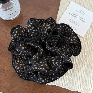 Macro view of floral print hair scrunchie with leopard pattern and contrast black edging