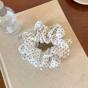 Detailed macro view of white polka dot chiffon scrunchie with elegant pearl pendant charm