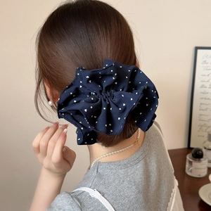 Close-up of navy blue scrunchie with white heart patterns worn on a low ponytail hair