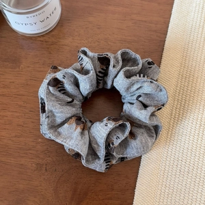 Close-up of zebra print scrunchie on a wooden desk with a minimalist perfume bottle