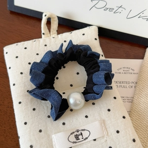 Detailed close-up of retro denim fabric scrunchie with large white pearl on beige dotted fabric
