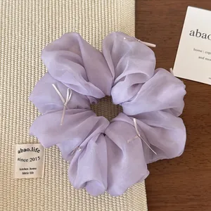 Detailed macro view of lilac organza scrunchie with delicate ribbon bows and soft texture