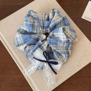 Dettaglio dell'elastico a quadretti blu con fiocco di pizzo e ciondolo a cuore