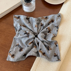Detail view of a grey scrunchie with cute dog prints on a rustic wooden table background