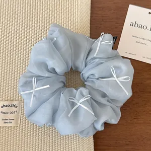 Detailed texture of light blue organza hair scrunchie with white ribbon bows