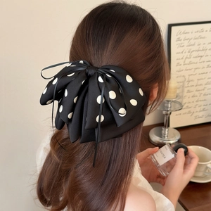 French vintage black hair clip with white polka dots and elegant ribbon bow on hair