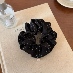 Detail of black polka dot hair scrunchie with pearl charm on vintage book
