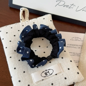 Detail of denim and black polka dot scrunchie with plastic ring on a wooden table