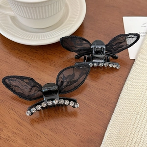 Elegant black lace butterfly hair claw clips with rhinestones on a wooden background