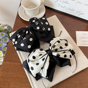Polka dot bow hair clip with black ribbons on vintage beige book and coffee cup