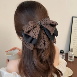 Detail of leopard print and black satin bow hair claw clip with rhinestone center