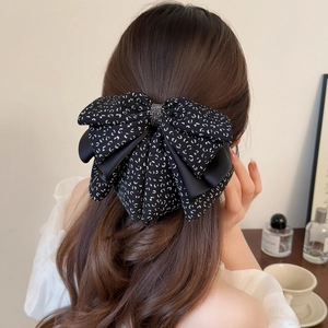 Detailed view of an elegant floral ribbon bow hair claw clip styled on a model ponytail