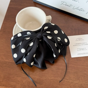 Detail of large polka dot bow hair clip with ribbons on a wooden surface