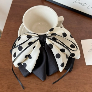 Detail view of large polka dot bow hair clip with ribbons on a wooden surface