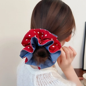 Detail view of red polka dot and blue denim scrunchie worn on a high ponytail bun
