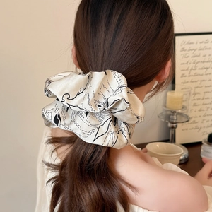 Elegant floral print hair scrunchie in warm white fabric shown on long wavy hair
