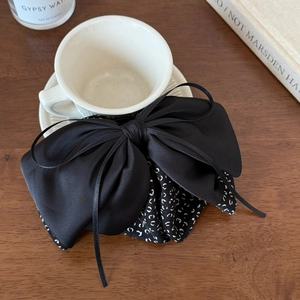 Detailed close-up of a vintage black satin ribbon bow clip on a rustic wooden desk