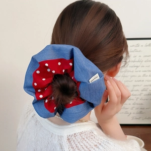 Detail of a handmade bicolor scrunchie with blue denim and red polka dots on a hair bun