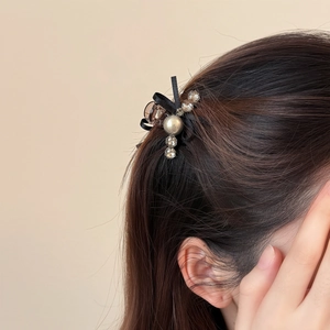 Elegant black ribbon bow hair claw with pearls and crystals shown on model hair