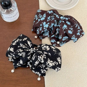 Sweet floral bow hair clips with pearl pendants on a rustic textured background