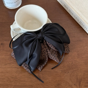 Detail of floral leopard print ribbon bow hair claw clip on an elegant wooden desk