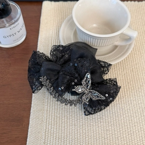 Détail d'une grande pince à cheveux en dentelle noire avec paillettes et papillon en strass