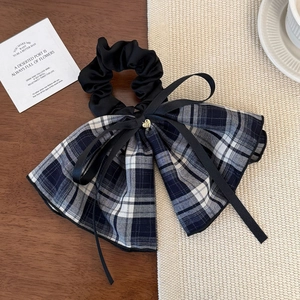 Detail of blue plaid bow hair scrunchie with black ribbons and gold heart pendant