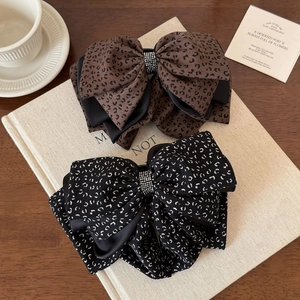 Detail of leopard print fabric bow hair clips with rhinestone centers on wooden desk