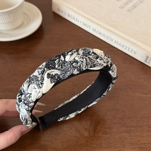 Close-up of wide braided headband featuring ink floral pattern on a vintage wooden table