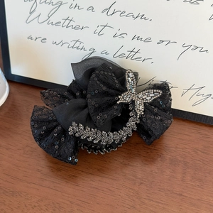 Détail d'une pince à cheveux en dentelle noire avec paillettes et papillon en strass brillant
