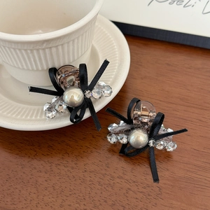 Exquisite mini hair claws with black ribbon bows and pearls on a warm wooden surface