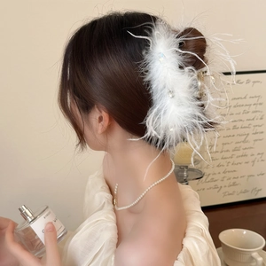 Detail of elegant white ostrich feather hair claw with sparkling rhinestones decoration