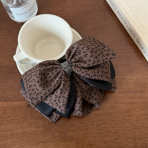 Detail of leopard print chiffon bow hair claw with sparkling rhinestone center on wood