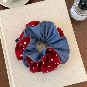 Detail of red polka dot scrunchie with denim texture layer and white stitching