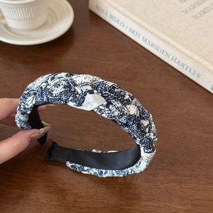 Detail of blue and white floral braided headband showing fabric texture on wooden table