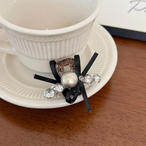 Exquisite bow hair claw clip with pearl and crystal beads resting on a white coffee cup