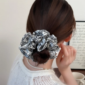 Elegant black and white paisley print oversized scrunchie worn on a high bun hairstyle