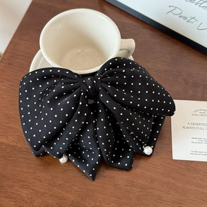 Detailansicht einer großen Haarklammer mit schwarzer Polka-Dot-Schleife und edlen Perlen