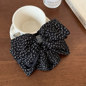 Detailed shot of black floral bow hair clip with sparkling rhinestones on a wooden surface