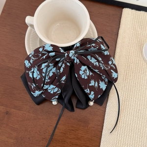 Détail d'une pince à cheveux à nœud floral avec tissu double couche et perles blanches