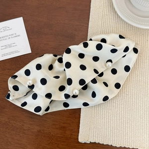 Detailed close-up of a large polka dot satin bow hair clip with elegant pearl accents