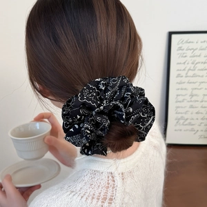 Fashionable black scrunchie with white cashew floral print on a soft fabric flower hair tie