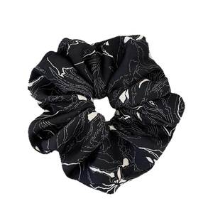 Elegant black scrunchie with white artistic line prints on a minimalist fabric hair tie