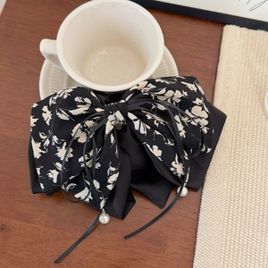 Détail d'un nœud à cheveux floral avec rubans et perles suspendues sur du bois