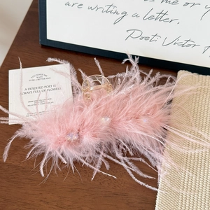 Close-up of fluffy pink ostrich feather hair claw clip with sparkling rhinestones and gold spring