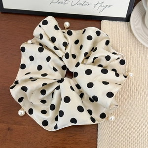 Detail of satin scrunchie featuring polka dot pattern with pearl fringe accents