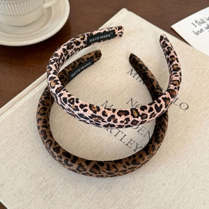 Close-up of leopard print velvet headbands with handmade label on textured book