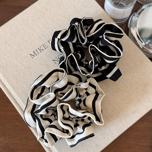 Oversized black and white striped scrunchie set with pleated ruffles on a book background