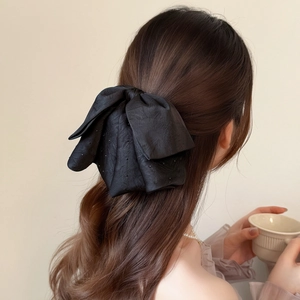 Elegant black satin bow hair clip with sparkling rhinestones worn on hair by a model